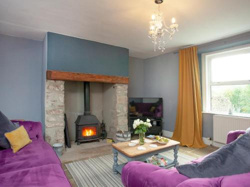 a living room with a purple couch and a fireplace at Uk45542-The Farm House in Sticklepath