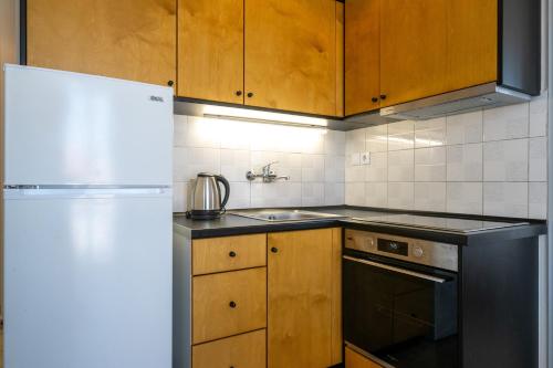 a kitchen with a white refrigerator and wooden cabinets at Mythos Suites-Apollo apartment in Methoni