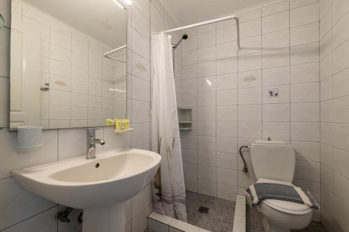 a white bathroom with a sink and a toilet at Mythos Suites-Apollo apartment in Methoni