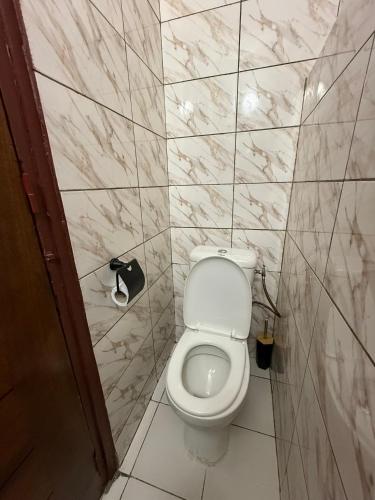 a bathroom with a white toilet in a tiled wall at Short-Term 2BR Apartment - 2 min from US Embassy, Cocody Riviéra Golf, Abidjan in Abidjan