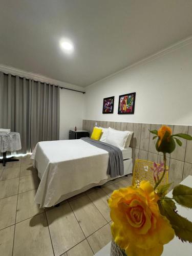 a bedroom with a bed and a table with flowers at Hotel Coqueiros in Valparaíso de Goiás