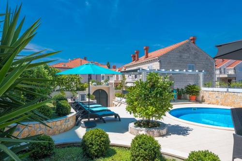 a house with a swimming pool and an umbrella at Villa Ida in Dubrovnik