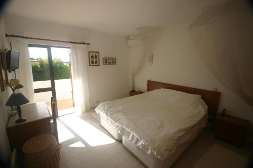 a bedroom with a white bed and a window at Casa Caracol in Praia do Carvoeiro