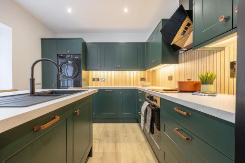 a kitchen with green cabinets and a washing machine at Large house in centre of Portrush with free parking x 2 cars in Portrush