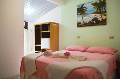a bedroom with two beds with pink sheets and towels at Pousada Raio de Sol in Fernando de Noronha