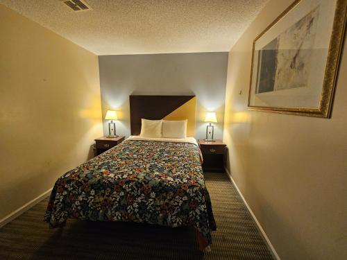 a hotel room with a bed with two lamps at MERRIMAC INN & SUITES in Williamsburg