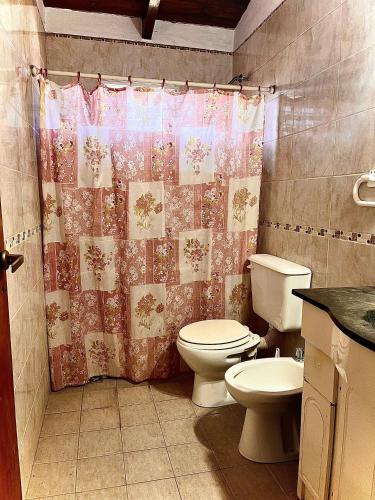 a bathroom with a toilet and a shower curtain at La casita del Malevo in San Francisco
