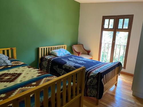 two beds in a room with green walls and a window at Quinta Vacacional Yunguilla, Santa Isabel, Azuay in Santa Isabel