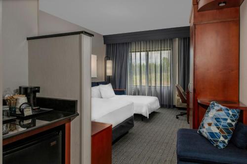a hotel room with a bed and a couch at Courtyard Pittsburgh Greensburg in Greensburg