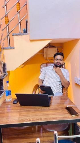 a man sitting at a desk with a laptop at KIARSH RESIDENCY HOME Stay in Varanasi