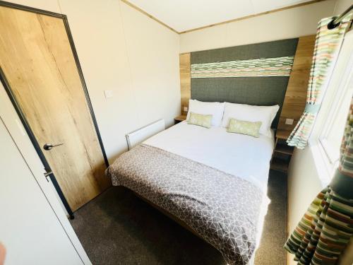 a small bedroom with a bed in a trailer at 2 Bedroom Caravan FF17, Fairway, Sandown, Isle of Wight in Isle of Wight