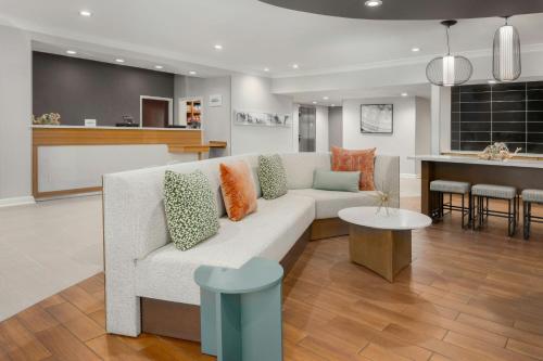 a living room with a white couch and a kitchen at SpringHill Suites Herndon Reston in Herndon