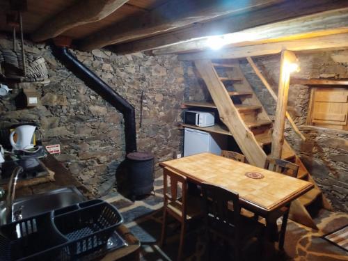 a small kitchen with a wooden table and a staircase at Casa da Avó Celta in Lousã