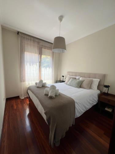 a bedroom with a large bed with white sheets and a window at El Ventanal de Pelayo in Gijón
