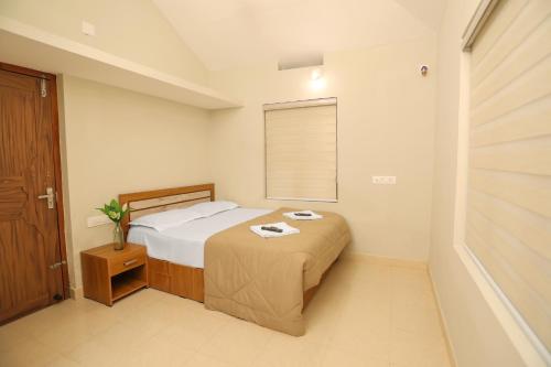 a small bedroom with a bed and a window at Nandanam Villa in Kaniyāmbetta