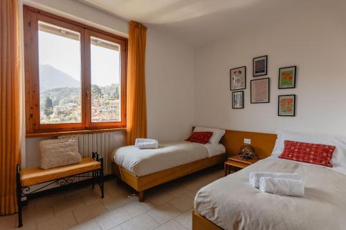 a bedroom with two beds and a large window at Villa Sanziana in Menaggio