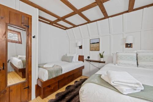two beds in a bedroom with white walls and wooden ceilings at Maple Pine w Hot Tub Pool Table 3min to Mount Snow in Dover