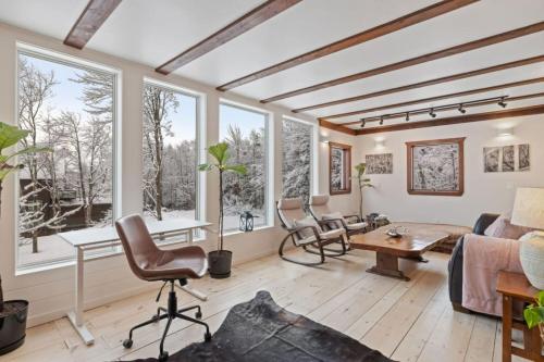 a living room with windows and a couch and a table at Maple Pine w Hot Tub Pool Table 3min to Mount Snow in Dover
