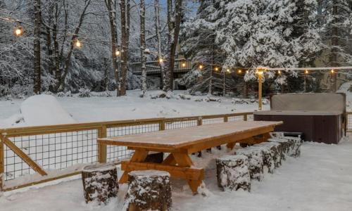 a wooden picnic table in the snow with lights at Maple Pine w Hot Tub Pool Table 3min to Mount Snow in Dover
