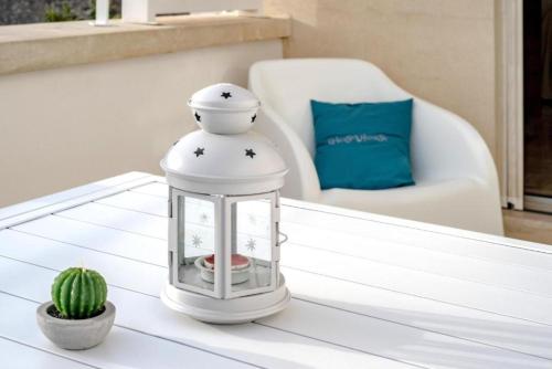 a white lantern sitting on a coffee table with a cactus at GIOSAHOUSE in Uggiano la Chiesa