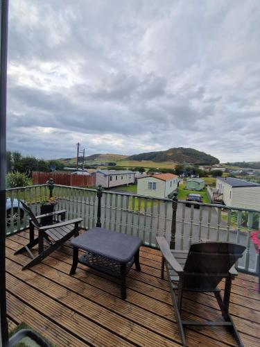a wooden deck with a table and chairs on it at Green Heaven at Clarach Bay Spacious 3 BedPet Friendly Luxury Steps from the Sea in Aberystwyth