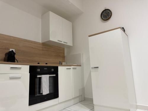 a kitchen with white cabinets and a black oven at Bonpas Appart Hotels in Avignon