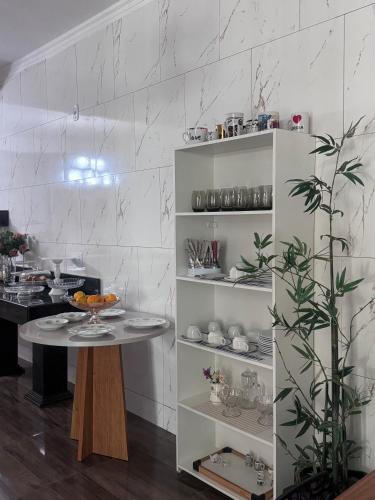a kitchen with a table and shelves in a room at Hotel Coqueiros in Valparaíso de Goiás
