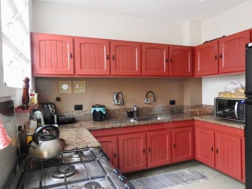 a kitchen with red cabinets and a sink and a stove at Casa para família com piscina in Guarujá