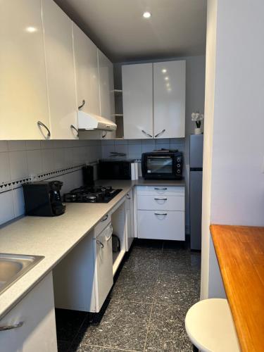 une petite cuisine avec des armoires blanches et un micro-ondes dans l'établissement Appartement Paris 16, à Paris