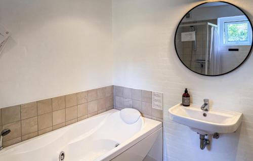 a bathroom with a sink and a tub and a mirror at Holiday Home A Hveyselsvej Rømø V in Rømø Kirkeby