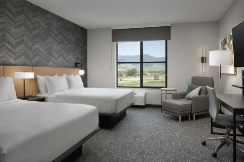 a hotel room with two beds and a desk at TownePlace Suites by Marriott Bozeman West in Bozeman