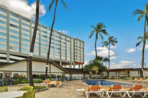 a hotel with a pool and chairs and palm trees at Best Western The Plaza Hotel Honolulu Airport - Free Breakfast in Honolulu