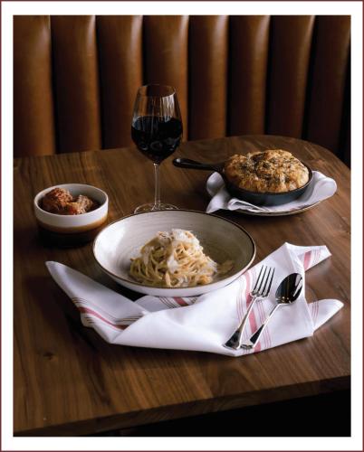a table with a plate of pasta and a glass of wine at Sechelt inn in Sechelt