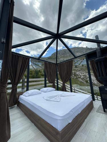 a bed in a room with a large window at Mariash Woodhouse I Sauna I Stargazing Glasshouse in Deçan