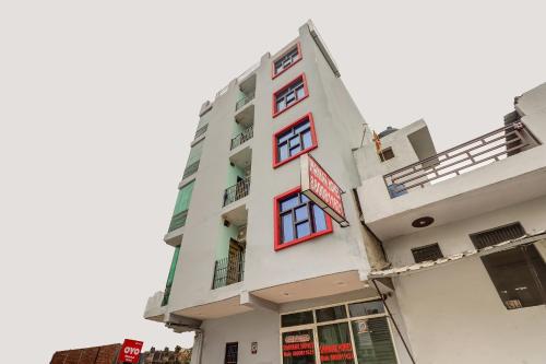 a tall white building with red windows at Super Hotel O Shankar Hotel Ghaziabad Railway Station in Ghaziabad
