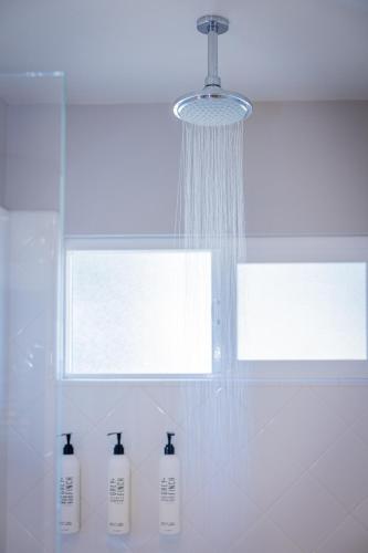 a bathroom with a shower with three bottles in front of a window at Marina Beach Motel in Santa Barbara