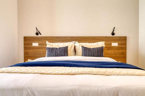 een groot bed met een houten hoofdeinde en kussens bij Funchal Acqua Blue 3H, a Home in Madeira in Panasqueira