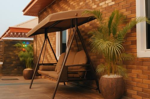 a swing in a porch with two plants at SEATWORK APARTMENT Enugu in Enugu Airport