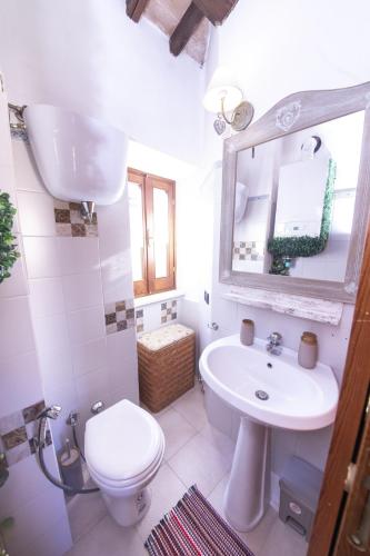 a bathroom with a sink and a toilet and a mirror at Casa Graziella Piccolo Pied à terre nel Castello di Palazzo d'Assisi in Palazzo