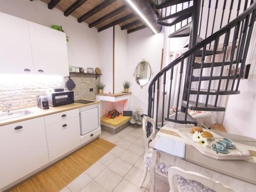 a kitchen with white cabinets and a black spiral staircase at Casa Graziella Piccolo Pied à terre nel Castello di Palazzo d'Assisi in Palazzo