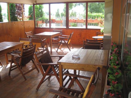a restaurant with wooden tables and chairs and windows at Motel Livija in Petrovec