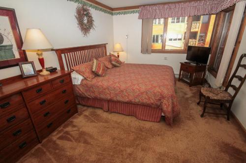 ein Schlafzimmer mit einem Bett, einer Kommode und einem Fernseher in der Unterkunft Mountainback #34, Corner in Mammoth Lakes