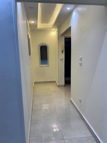 a hallway with white walls and a tile floor at Modern apartment in Sheraton in Kafr Abû Sîr