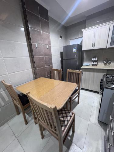 a kitchen with a wooden table and chairs and a refrigerator at Modern apartment in Sheraton in Kafr Abû Sîr