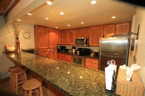 a kitchen with wooden cabinets and a stainless steel refrigerator at Mountainback #117, Loft in Mammoth Lakes