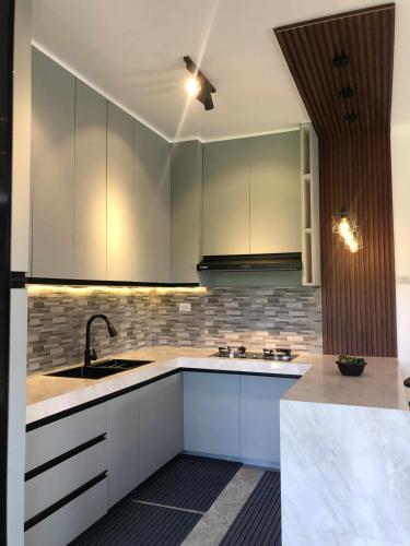 a kitchen with white cabinets and a ceiling fan at The CozyNest Camiguin Homestay in Mambajao