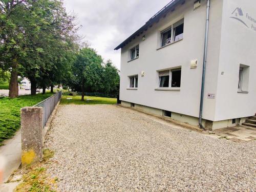 a white building on a gravel road next to a fence at Ferienwohnung Sonnendeck einladend und freundlich in Laupheim