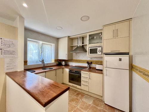 een keuken met witte apparatuur en een houten aanrecht bij La Ria - by Wehomes - Mogro River in Miengo