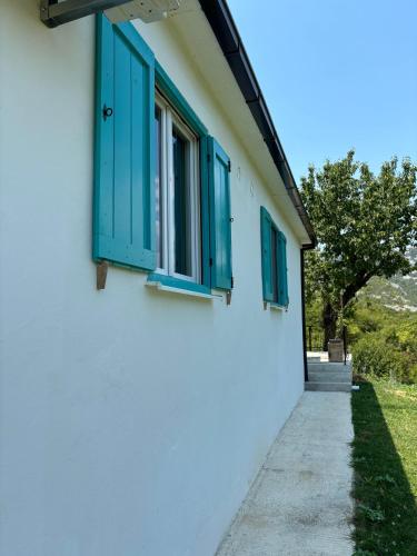 a white building with blue windows and a sidewalk at Deaf Valley Apartment 2 in Reljići