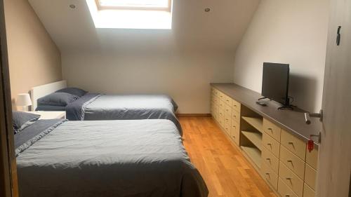 a attic bedroom with two beds and a tv at Villa 8 chambres pour 20 personnes in Charleroi